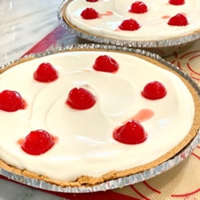 Pineapple Cheesecake with a citrus creamy top layer and cherries for garnish 