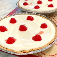 Pineapple Cheesecake with a citrus creamy top layer and cherries for garnish 