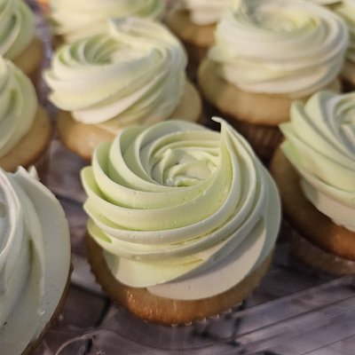  12 Vanilla Cupcakes With Light Green Buttercream Frosting. 